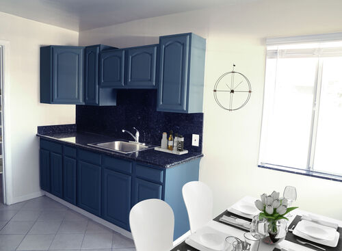 Kitchen with blue cabinets and black granite countertops with grey tile floors and a white table