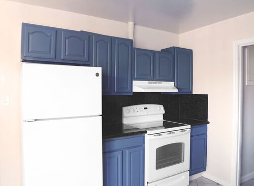 Kitchen with white stainless steel appliances and blue cabinets with black granite counters