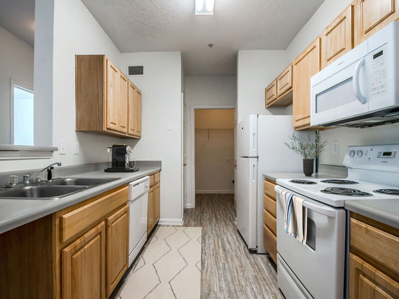 Image of galley kitchen interior with range, microwave, refrigerator, and dishwasher.