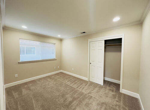 Bedroom with recessed lights tan carpets and white trim