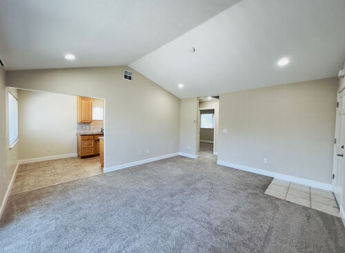 Large living room with tile entryway leading to carpeted main area and kitchen area