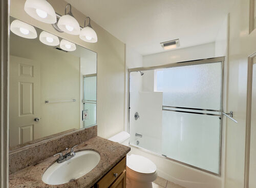 Bathroom with sliding glass panels granite countertop and mirror below vanity lights