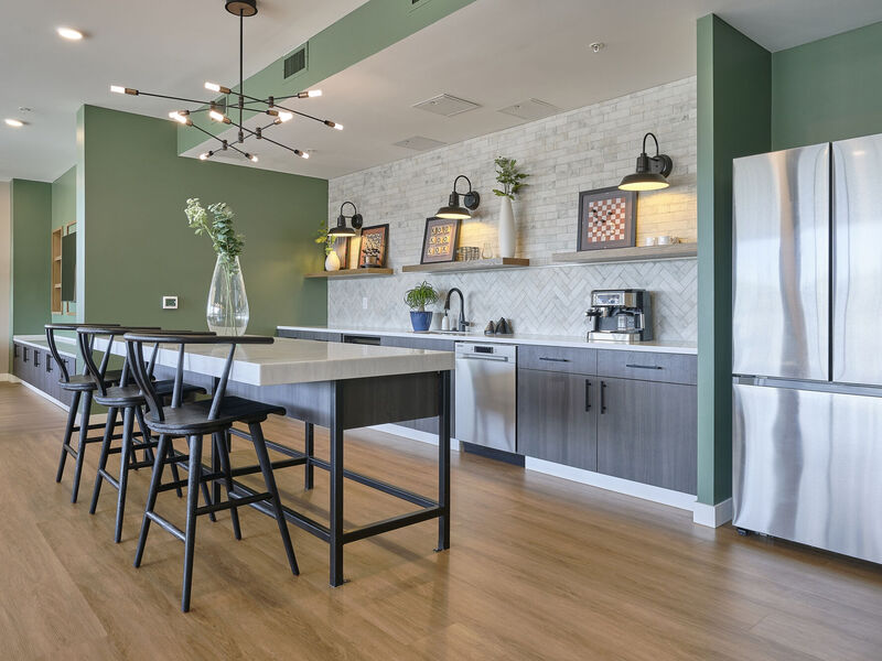 Clubhouse kitchen with refrigerator, dishwasher, coffee pot and island  with barstools.