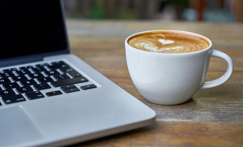 a laptop computer and coffee mug sitting on a desk