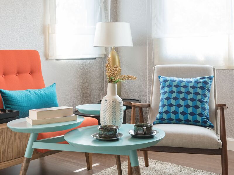 Two arm chairs and side table with a vase and coffee cups on top