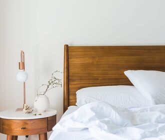 Westminster Manor - stock photo of a headboard and bed with a nightstand, flower vase, and lamp on top