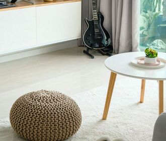 Stock photo of a living Room area with guitar and tv in the distance with a coffee table and slippers on rug
