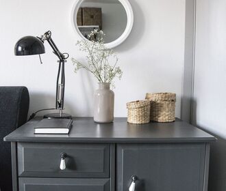 Westminster Manor - stock photo of a cabinet table that has a plant, book, lamp and 2 small baskets on top with a mirror hanging on the wall