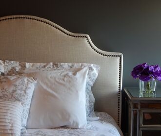 Versa at Civita - stock photo of a headboard and bed with a nightstand, flower vase, and lamp on top