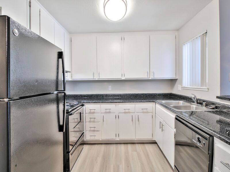 Kitchen with white cabinets, stainless steel appliances and black counter tops.