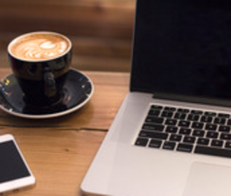Stock image of computer, cell phone, and cappuccino.