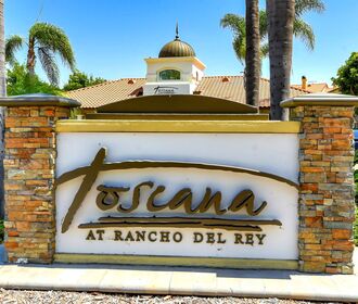 Toscana at Rancho Del Rey monument sign with script logo and leasing office in background.