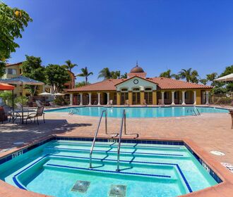 Spa with view to resort-style pool area, picnic tables, lounge seating, and gas grills.