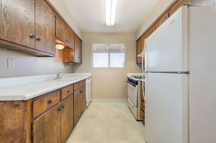 Galley kitchen with window, refrigerator and gas range