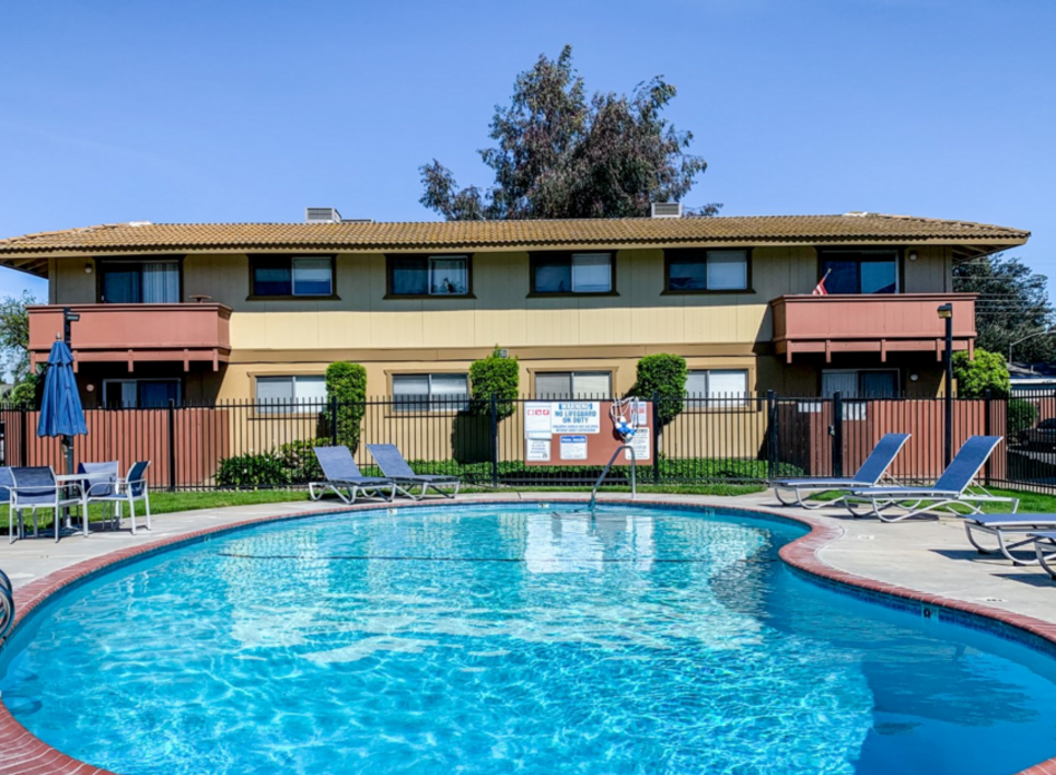 Pool and deck surrounded by iron fence and apartment buildings