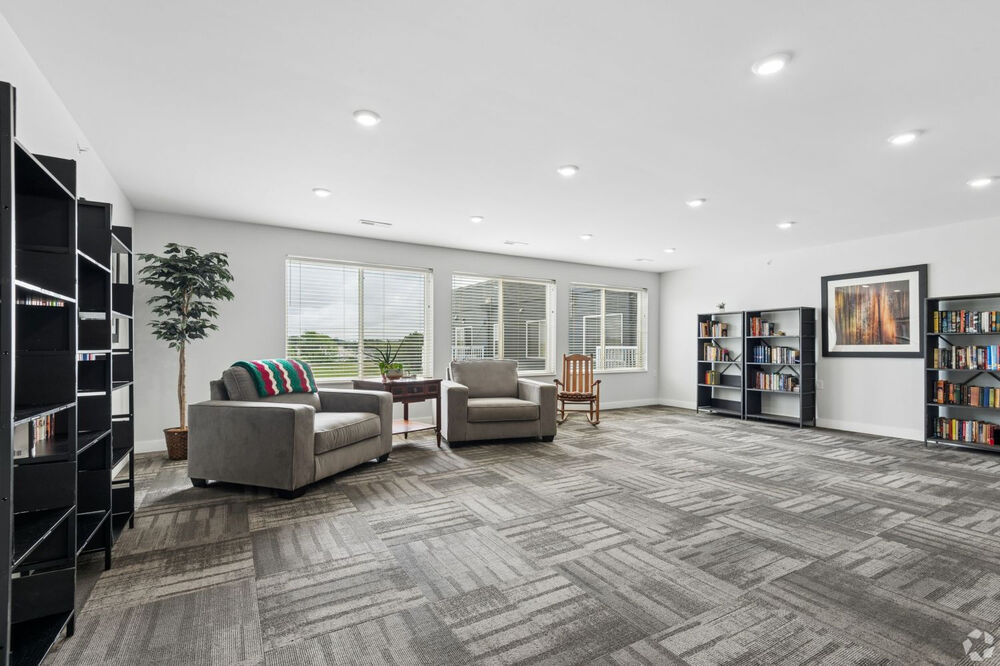 Picture of the community room with tables and ample natural light from windows in the Alice Place Senior Living Apartments in Monroe, WI.