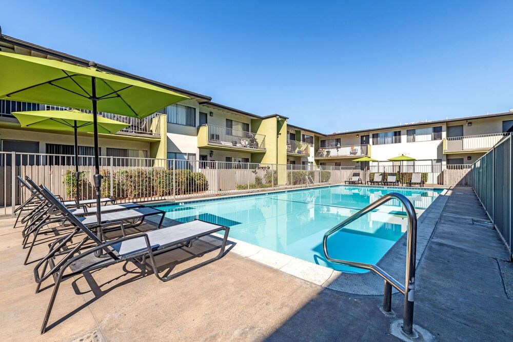 Swimming pool with lounge chair seating and umbrellas.