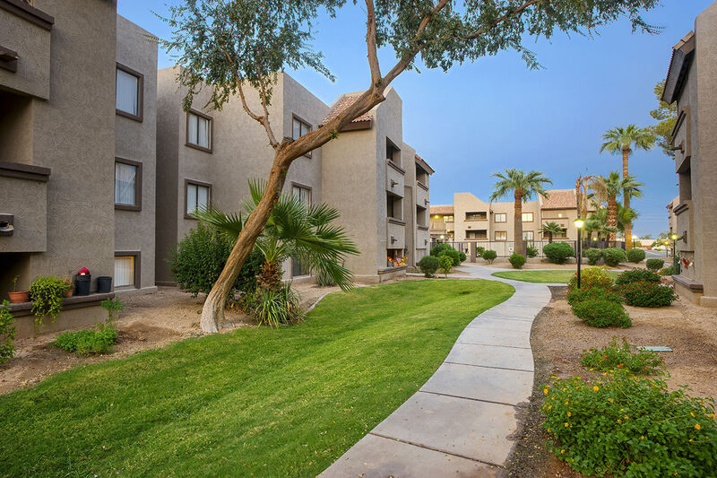 grassy area and walkway in between 3 story apartment buildings at Park at 55th