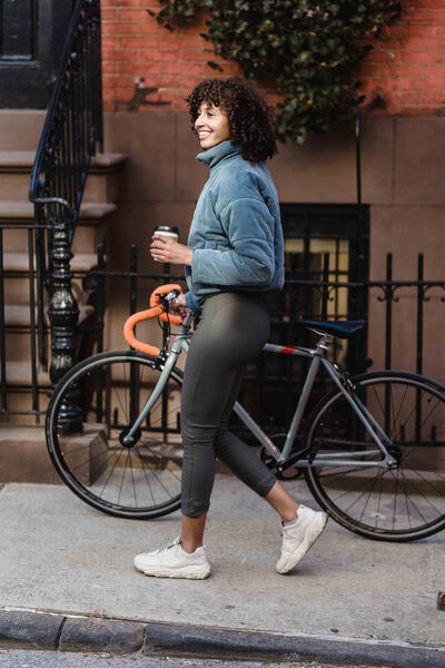 woman holding coffee and walking bike