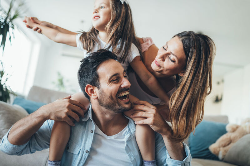 Smiling couple standing together with child on man's shoulders
