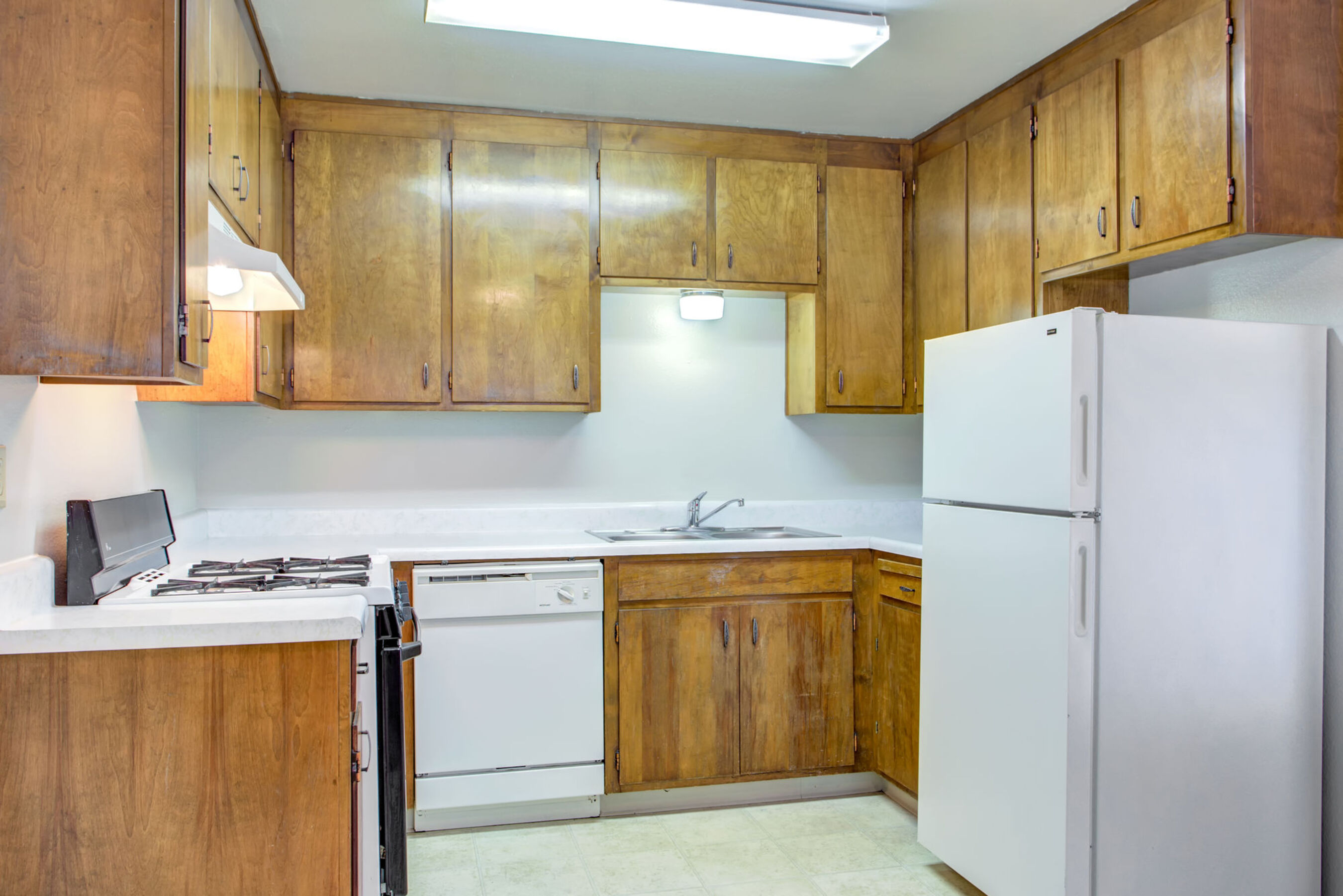 kitchen area with stained cabinetry and white appliances.