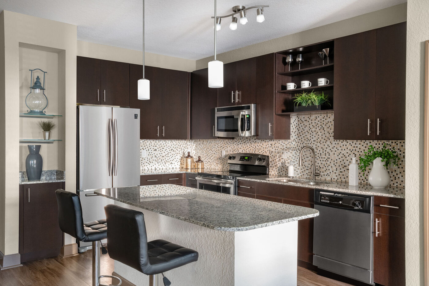 The Courtney at Universal Boulevard - Model kitchen with all stainless front appliances, large counter tops, island, and ebony cabinets.